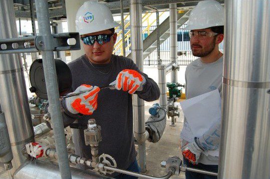 2 workers dressed in appropriate PPE work on piping at the Center for Petrochemical, Energy, and Technology at San Jacinto College